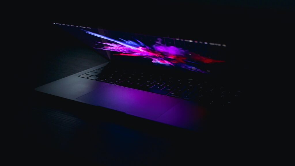 A laptop displaying a vibrant abstract design in low light, highlighting artistic and digital design concepts.